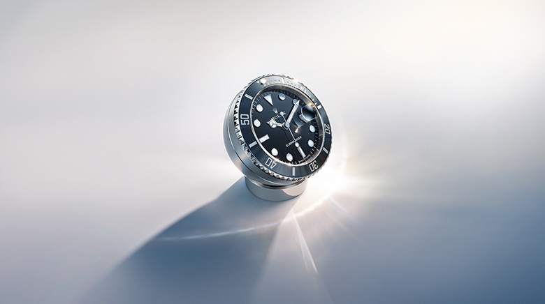 Die Rolex Submariner Date Tischuhr auf einer hellen Fläche im Lichtstrahl