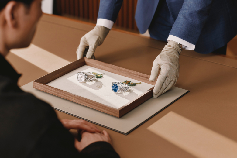 Ein Berater präsentiert zwei Rolex Armbanduhren auf einem Tablett