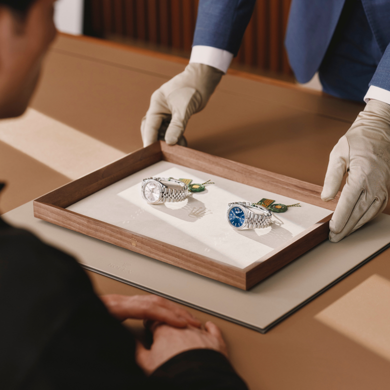 Ein Berater präsentiert zwei Rolex Armbanduhren auf einem Tablett