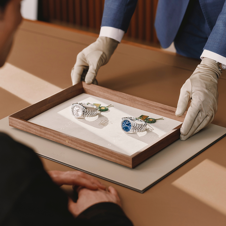 Ein Berater präsentiert zwei Rolex Armbanduhren auf einem Tablett
