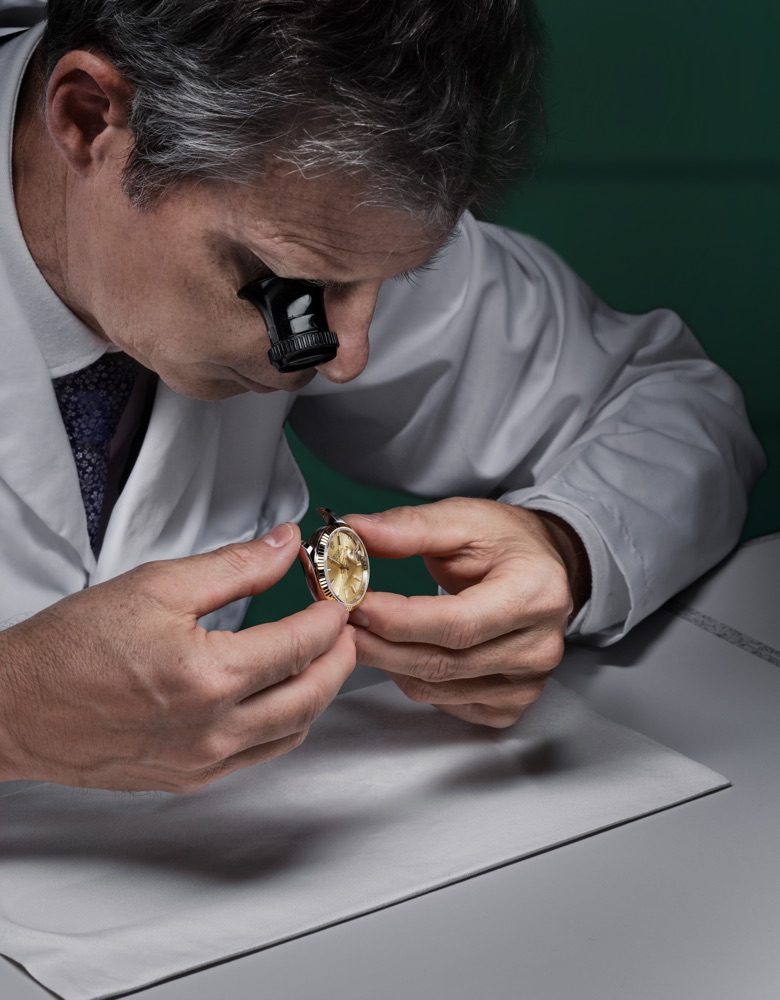 Ein Rolex Uhrmacher untersucht ein Uhrwerk unter der Lupe