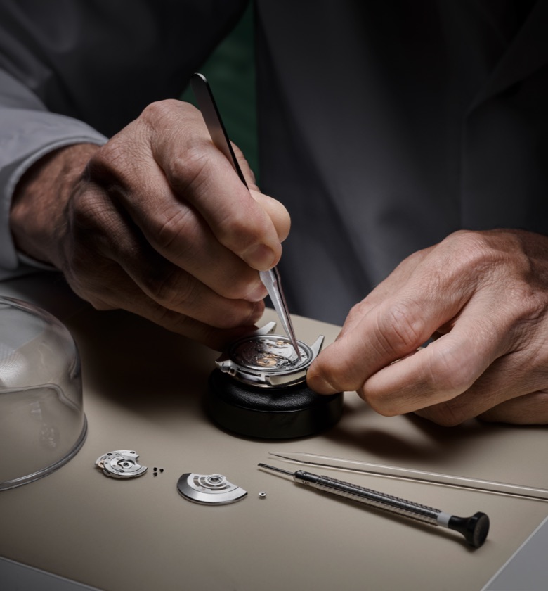 Ein Rolex Uhrmacher arbeitet mit der Pinzette an einem Uhrwerk