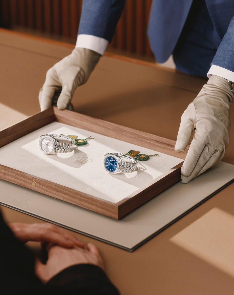 Zwei Rolex Armbanduhren werden auf einem Präsentationstablett entgegengenommen